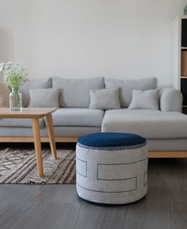 A blue and white pouf ottoman in a neutral living space.
