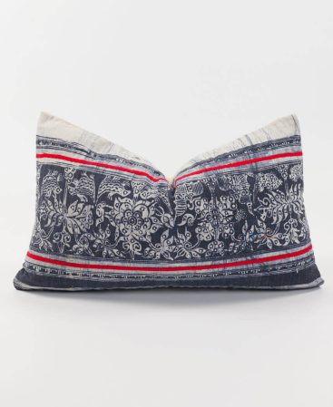 A boho cushion cover with tribal fabric and red stripes.