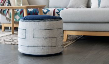 A large white ottoman pouf with blue dyed stripes.