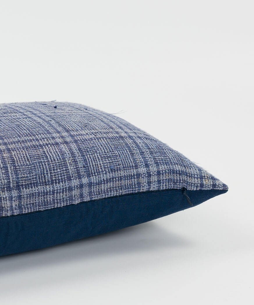 A plaid cushion with various blue hues and colors.