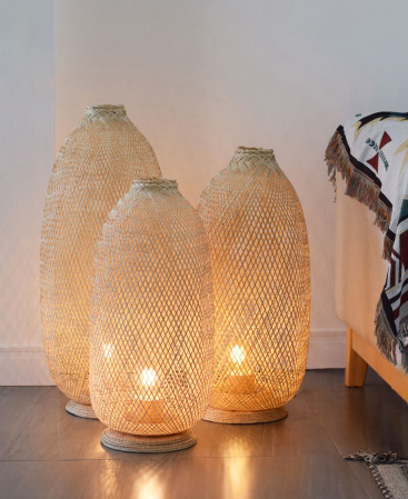A bamboo rattan floor lamp set comprising of three tall standing lamps.