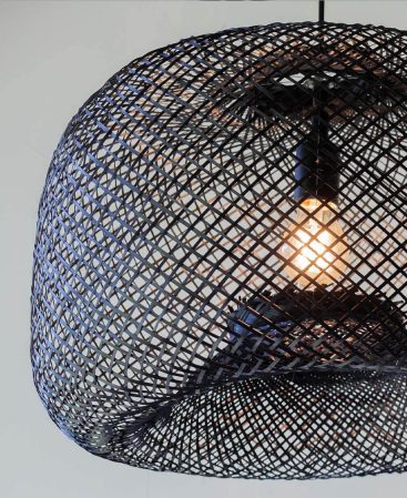 Close up photo of a dyed black light fixture made of woven bamboo wood.