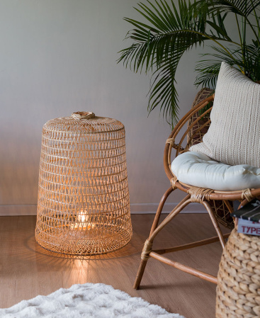 Sustainable bamboo wood floor lamp next to a rattan chair.
