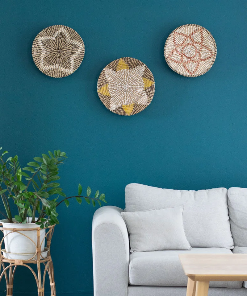 Three woven wall art bowls above a sofa.