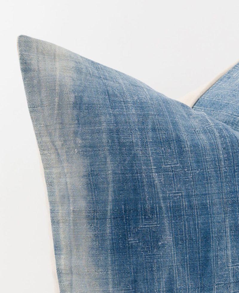 Worn indigo fabric cushion with white stripes and light batik designs.